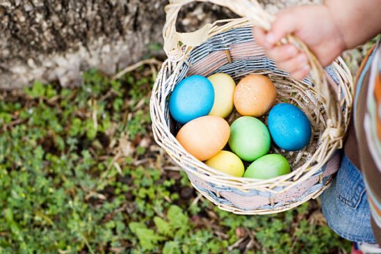 Panier tenu par un enfant avec des oeufs colorés